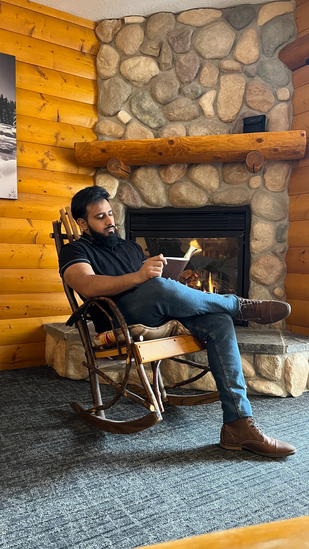 Ahmad Ali reading beside a stone fireplace in an Alberta lodge