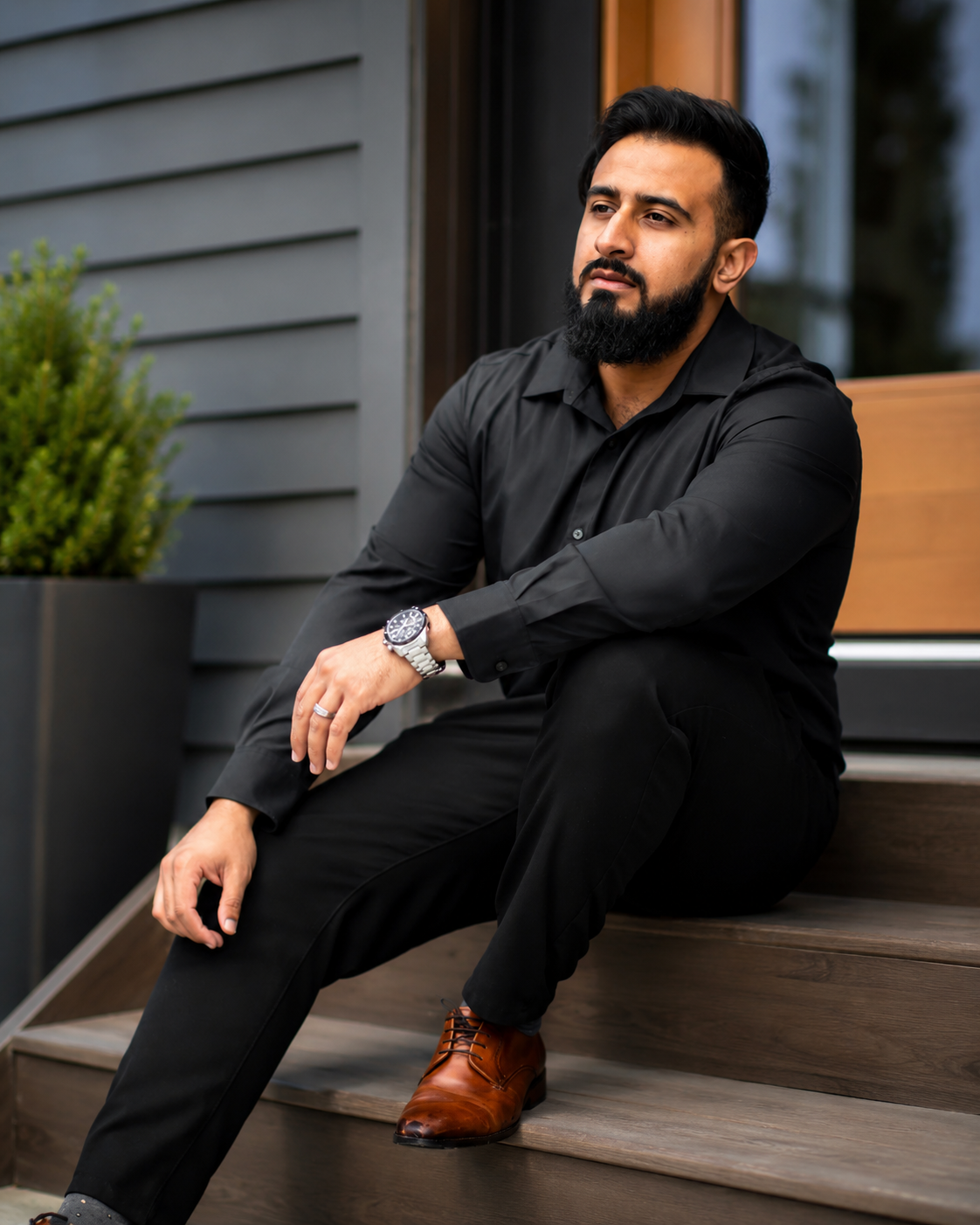 Ahmad Ali, Calgary Realtor, seated on the front steps of a modern home