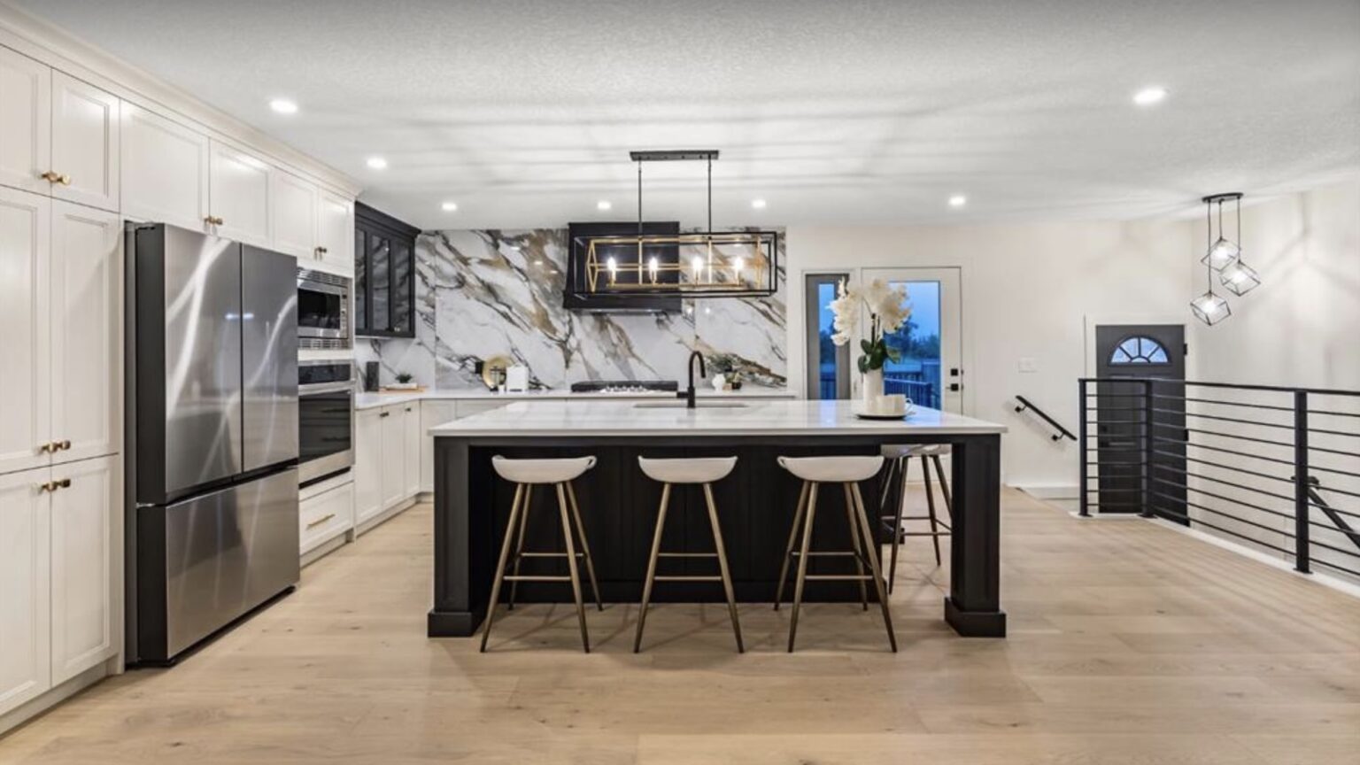 Finished kitchen in a Calgary custom build with a black island and marble backsplash